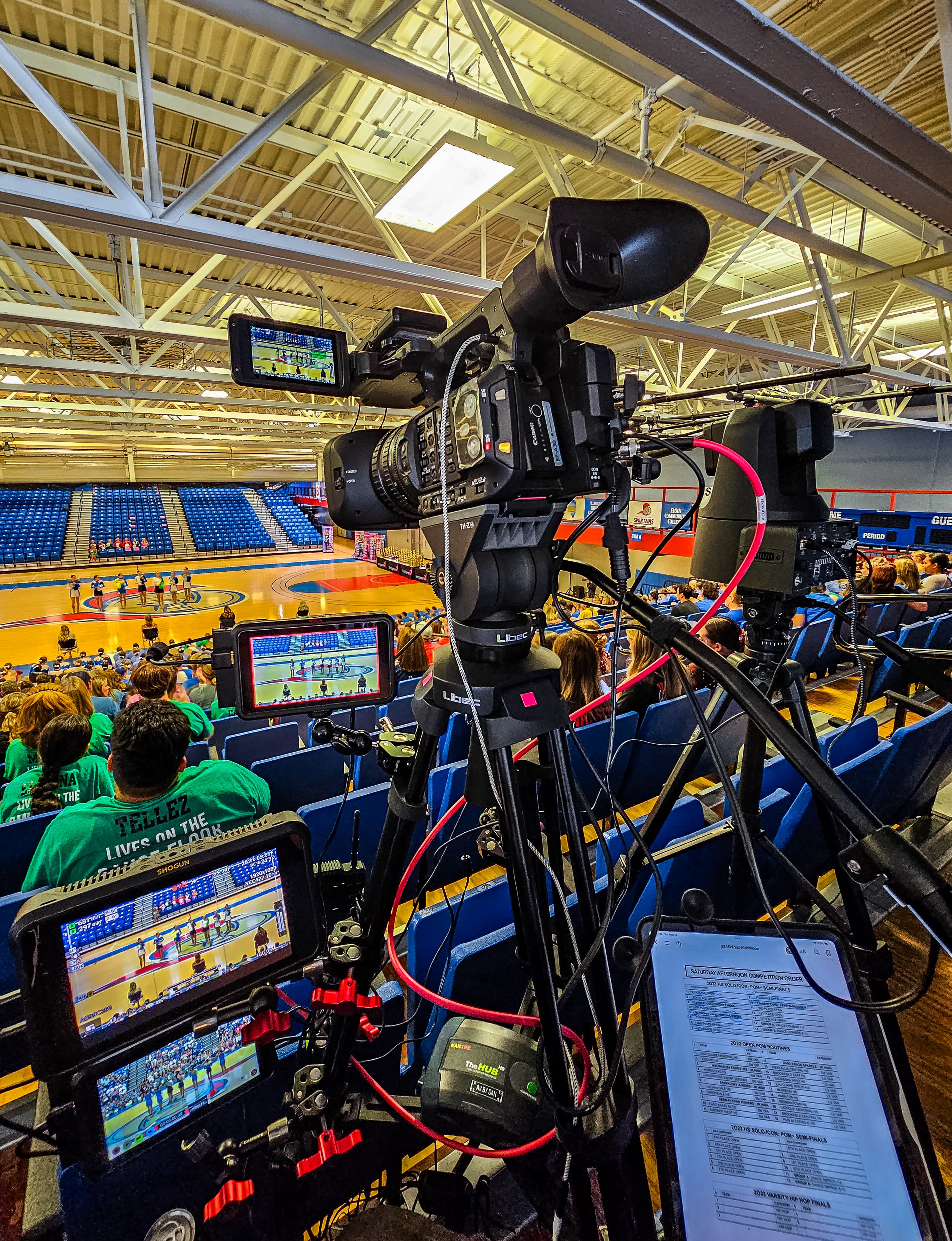 Professional video camera setup with monitors filming a dance competition in a large stadium.