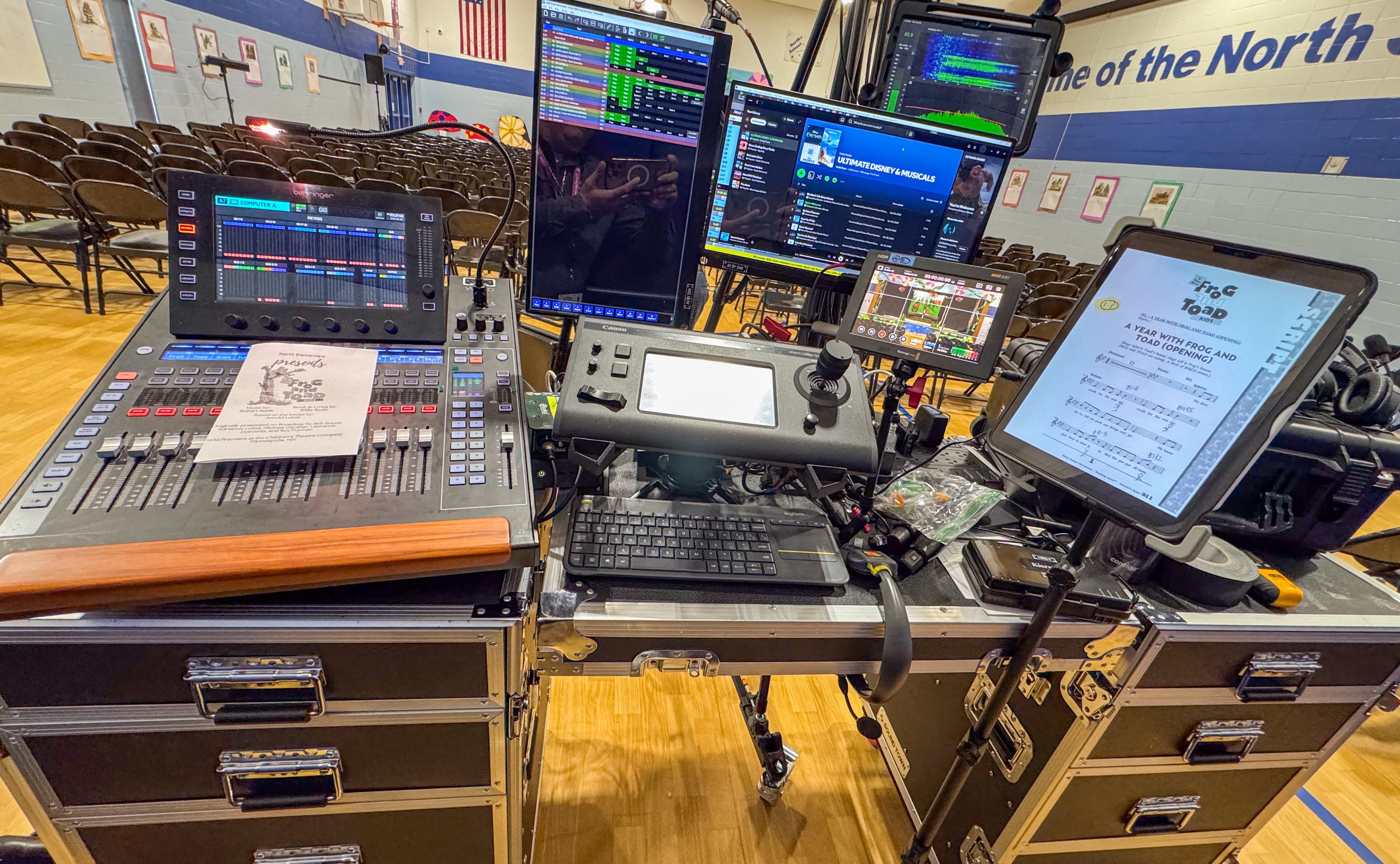 Audio mixing console and monitors set up in a gymnasium for a school theater production.